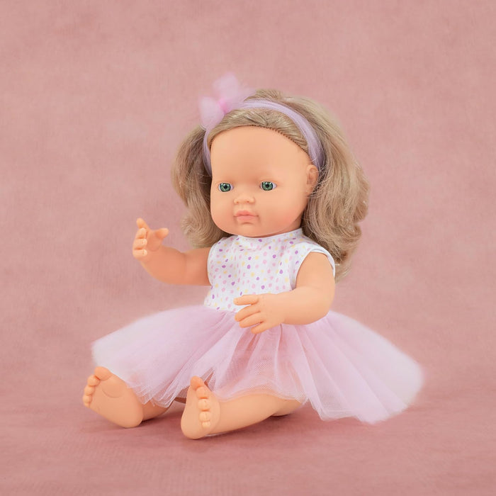 Sitting baby doll with dark blonde hair and green eyes in a polka dot top, pink tulle tutu, and bow headband.