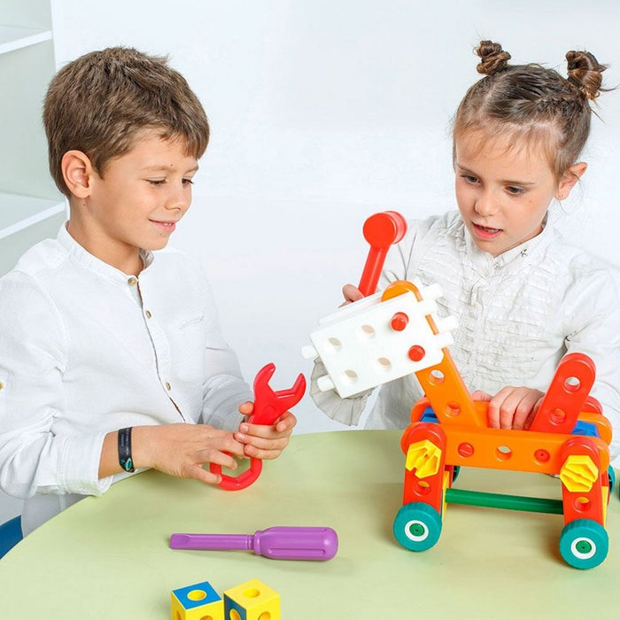 Two children building a colorful toy vehicle with plastic nuts, bolts, a red wrench, and a purple screwdriver.