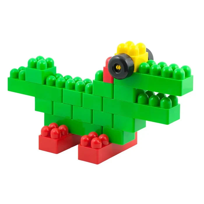 Green toy crocodile built from plastic building blocks with red feet, a yellow head, and a black wheel eye.