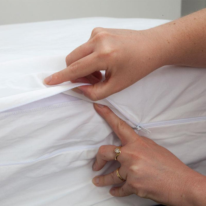 MiteGuard cot mattress cover with flap being tucked under the zipper for a secure fit, designed to protect against mites.