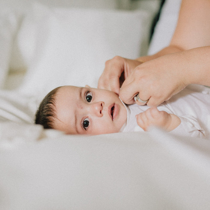 Baby lying on MiteGuard Cot Mattress Cover in a crib, showing a soft, protective mattress cover designed for baby cots.