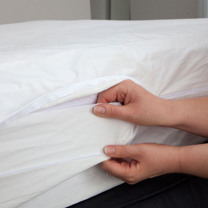 MiteGuard cotton mattress cover with zipper and flap for secure fit and protection against mites on a bed.