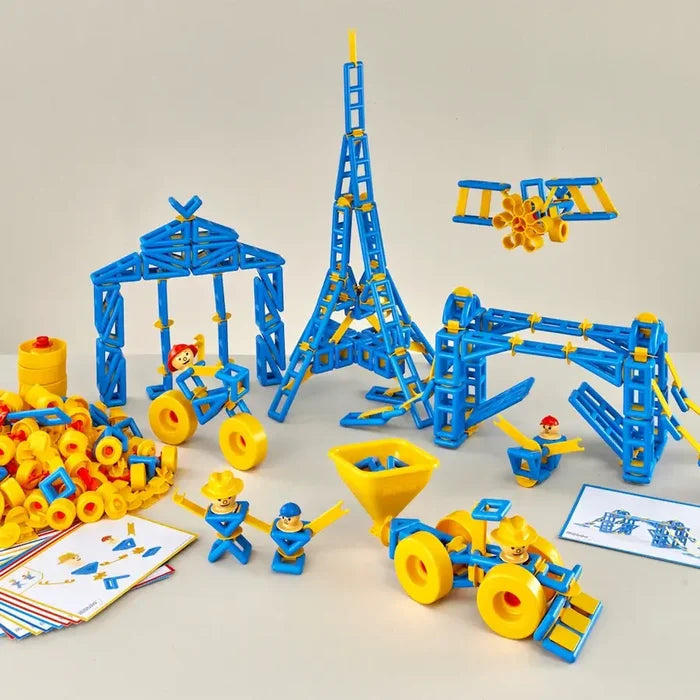 Blue and yellow plastic construction pieces built into a tall tower, archway, and vehicles with small toy figures.