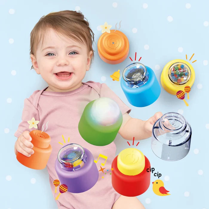 Smiling baby with colorful cylindrical sensory blocks that light up, rattle, and feature various sound icons.
