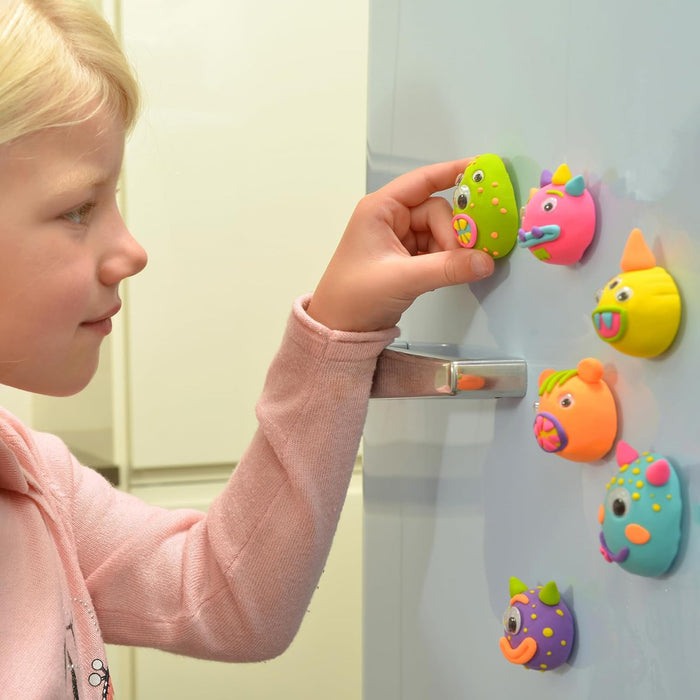 Child placing colorful, textured monster magnets with googly eyes onto a light blue refrigerator door.