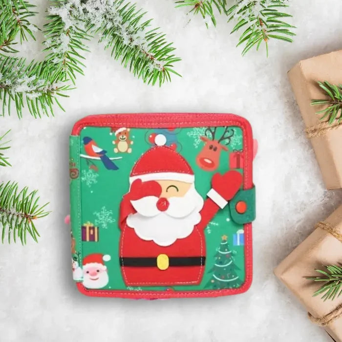 Green fabric busy book featuring a felt Santa Claus, surrounded by snowy pine branches and wrapped holiday gifts.