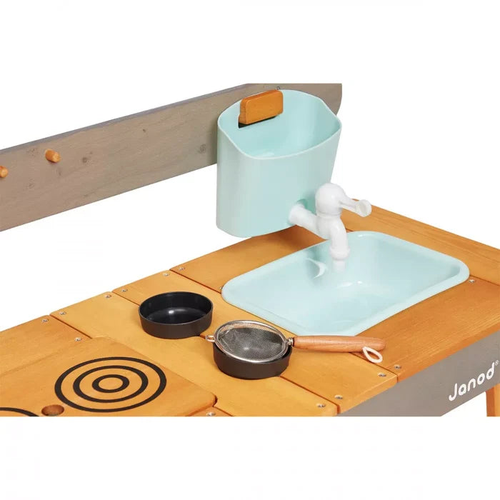 Wood outdoor mud kitchen with mint green sink, matching water bucket, white faucet, and toy kitchen pans.