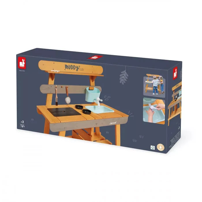 Dark blue box for a Janod wooden outdoor kitchen with a light blue sink, black burners, and hanging play utensils.