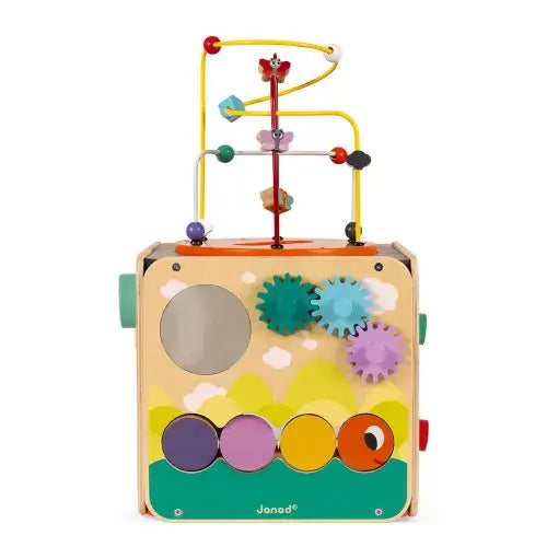 Wooden activity cube with wire bead maze, colorful spinning gears, mirror, and rotating cylinders on a painted landscape.