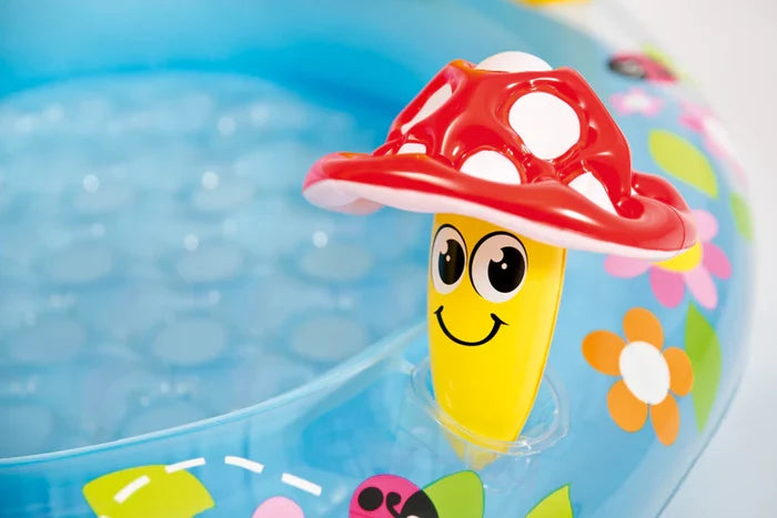 Blue inflatable pool with a yellow smiling mushroom toy, red and white spotted cap, and colorful floral patterns.