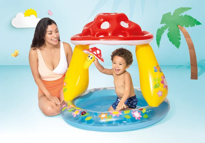 Inflatable baby pool with red spotted mushroom canopy, yellow pillars and floral base. A woman and toddler play.