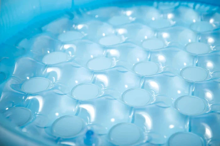 Close-up of the cushioned light blue inflatable floor of a baby pool with circular bubble indentations.