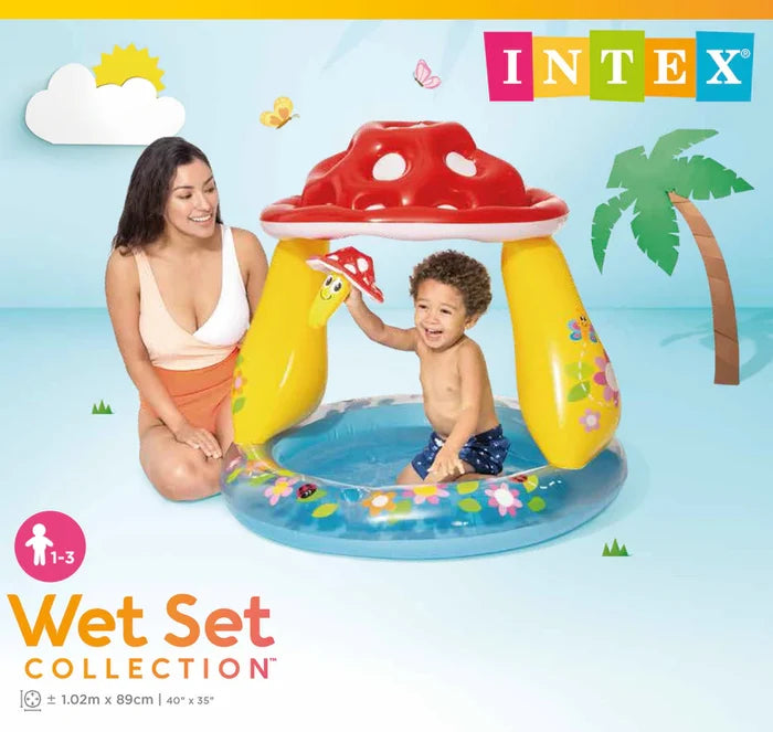 Inflatable baby pool with red mushroom canopy, yellow pillars, and blue floral base; woman and child playing inside.