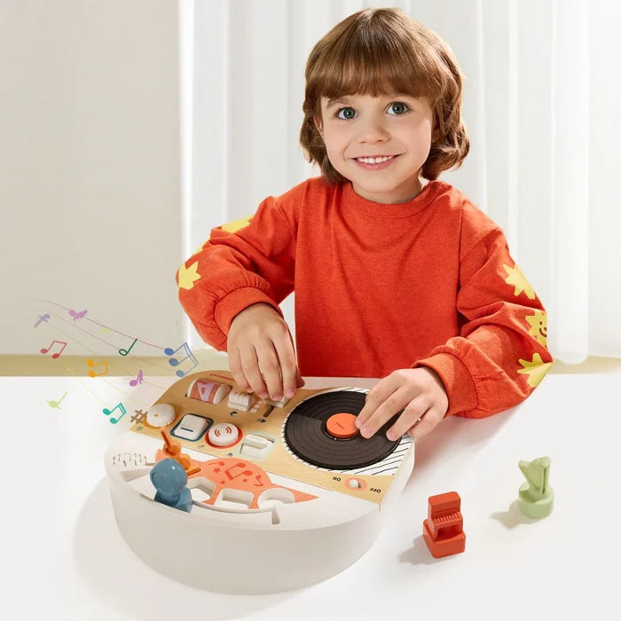 Child playing with a wooden DJ busy board featuring a turntable, sliders, and colorful floating musical note graphics.