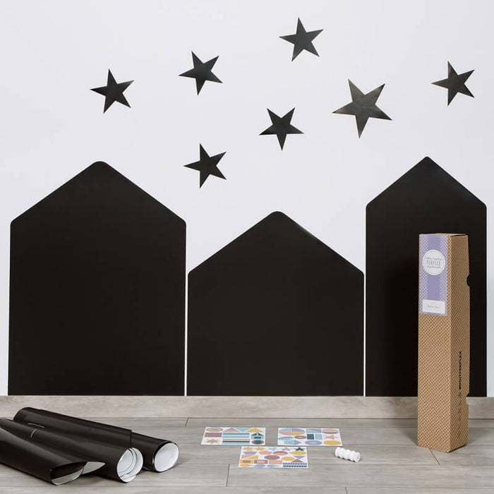Three black house-shaped magnetic chalkboards on a white wall with star magnets and colorful shape accessories.