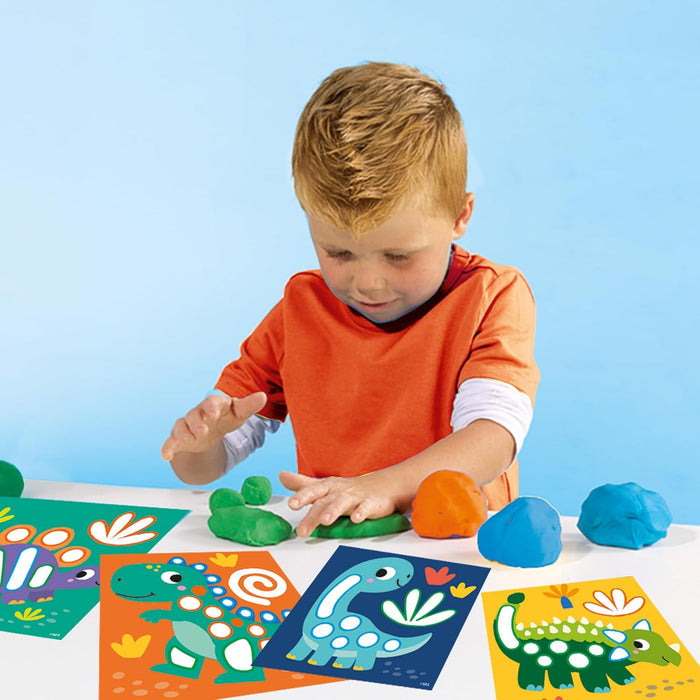 Young boy shaping green, orange, and blue dough on colorful dinosaur-themed activity cards.