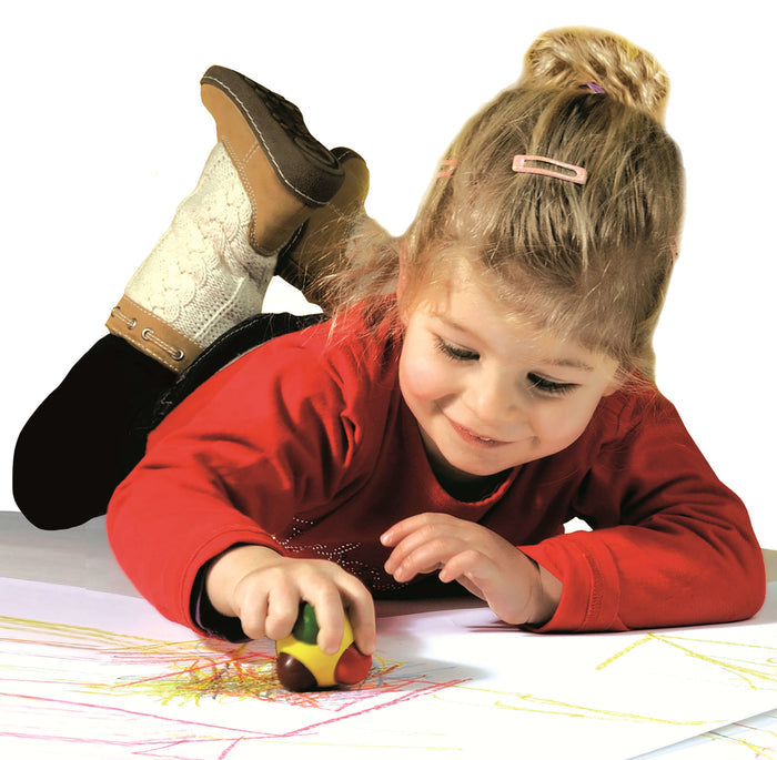 A child uses a round, multi-colored ball crayon with chunky tips to draw on large white paper.