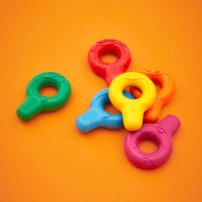 Six brightly colored, ring-shaped crayons for toddlers scattered on a solid orange background.