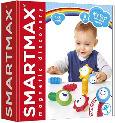 Red SmartMax box showing a baby playing with colorful magnetic pieces with smiley faces, stars, and rattles.