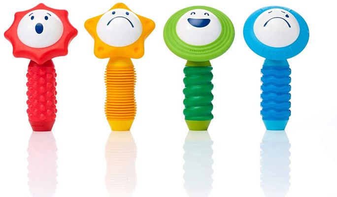 Four colorful sensory toys with varied facial expressions and textured handles in red, yellow, green, and blue.