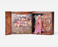Open wooden box with a blonde fairy doll in a pink dress, small drawers, and a magical forest illustration.