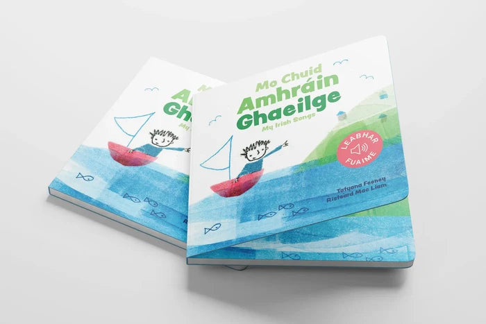 Two children's Irish books with watercolor art of a boy in a sailboat on a blue sea with a pink sound icon sticker.