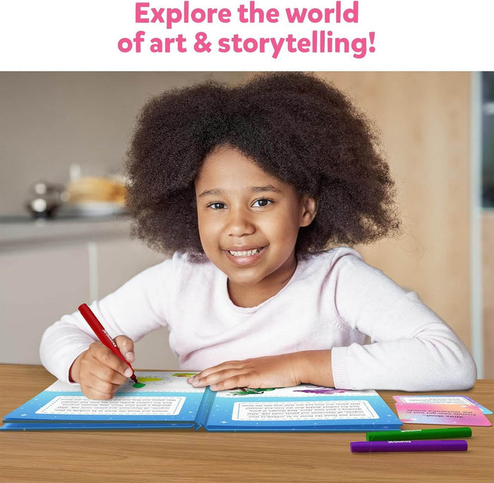 Smiling young girl with curly hair drawing in a blue storybook art kit with colorful markers on a wooden table.