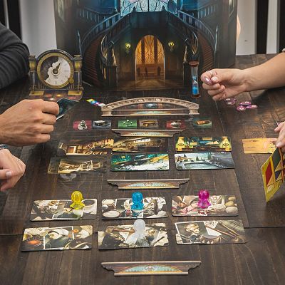 Mysterium board game in play with colorful pawns, illustrated cards, a clock, and a mansion screen on a dark wooden table.