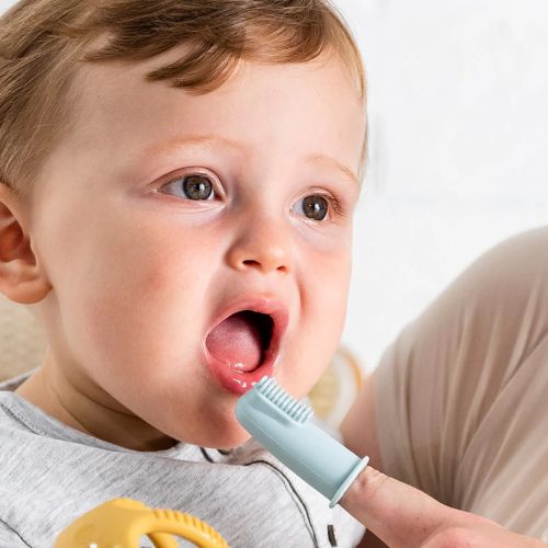 Light blue silicone finger toothbrush with soft bristles on an adult's finger near a baby's open mouth.
