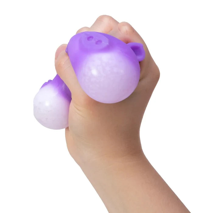 Hand squeezing a purple and white pig-shaped stress toy, showing its translucent bulging texture.