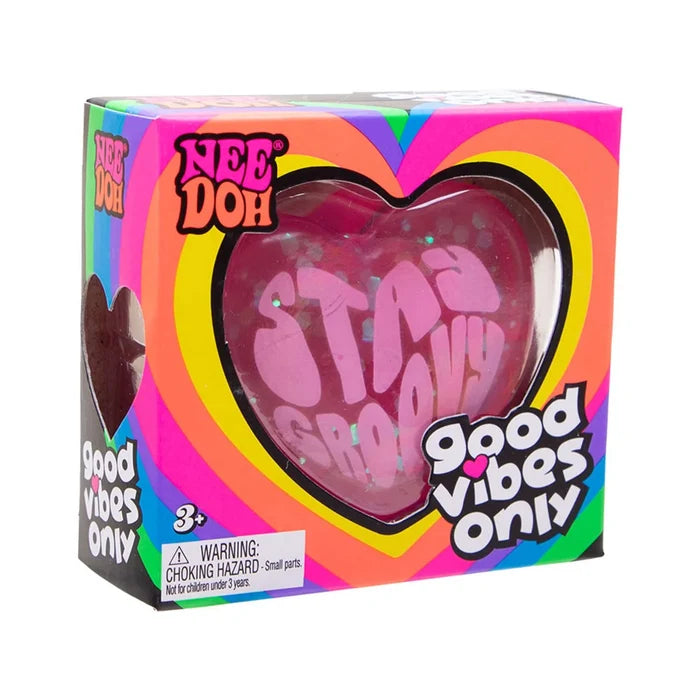 Pink heart-shaped squishy toy with "STAY GROOVY" inside a rainbow-patterned box with a heart-shaped window.
