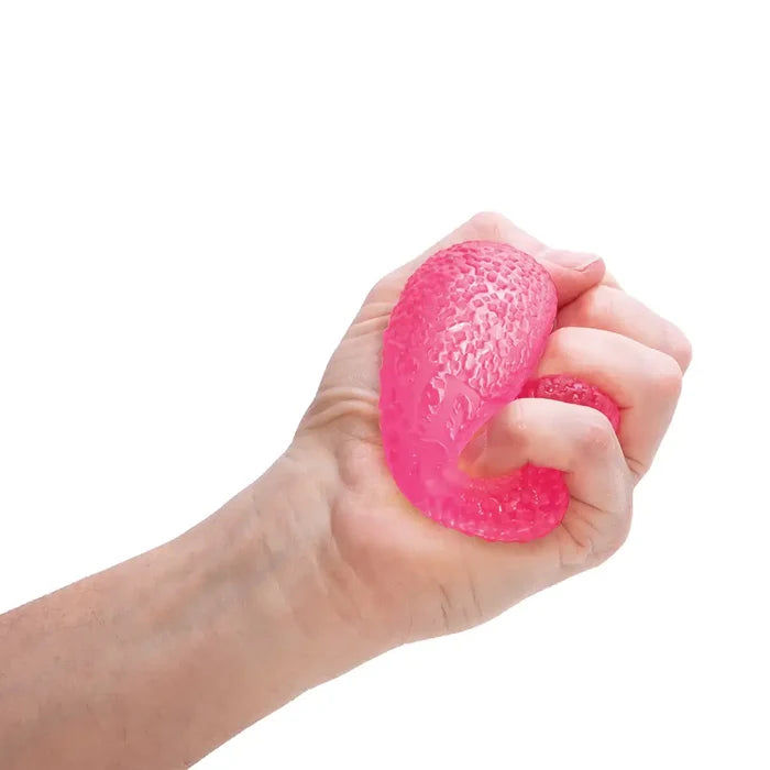 A hand squeezes a translucent pink, bumpy-textured squishy ball.