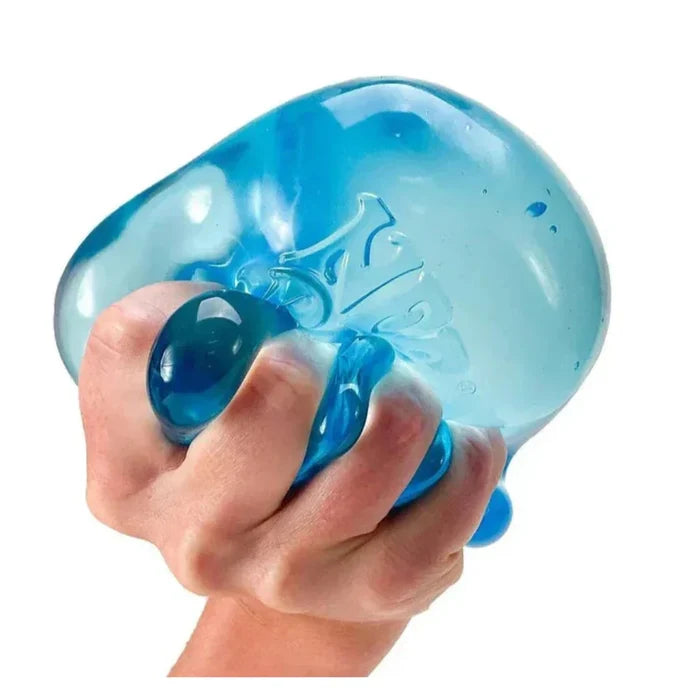 Hand squeezing a large, translucent blue gel-filled stress ball with a faint embossed logo.