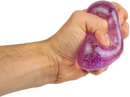 Hand squeezing a translucent purple squishy toy filled with sparkling glitter.