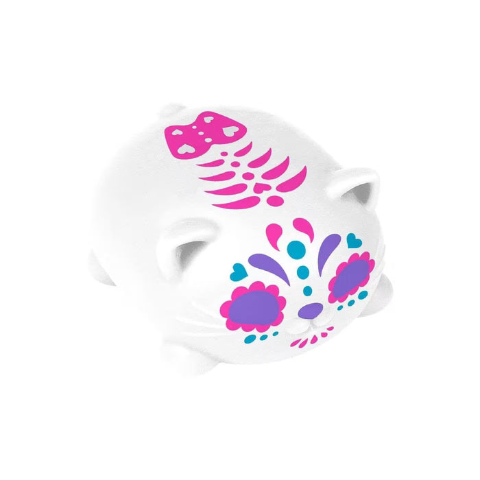 White cat-shaped squishy toy with pink, purple, and blue sugar skull face designs and a pink skeletal pattern on its back.