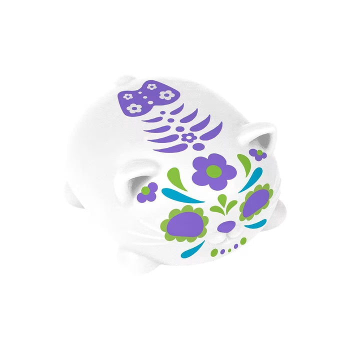 White cat squishy with purple and green sugar skull floral decorations and a stylized skeleton spine on its back.