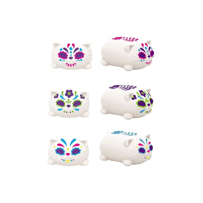 White cat-shaped squishy toys with colorful sugar skull patterns in pink, purple, green, and blue.