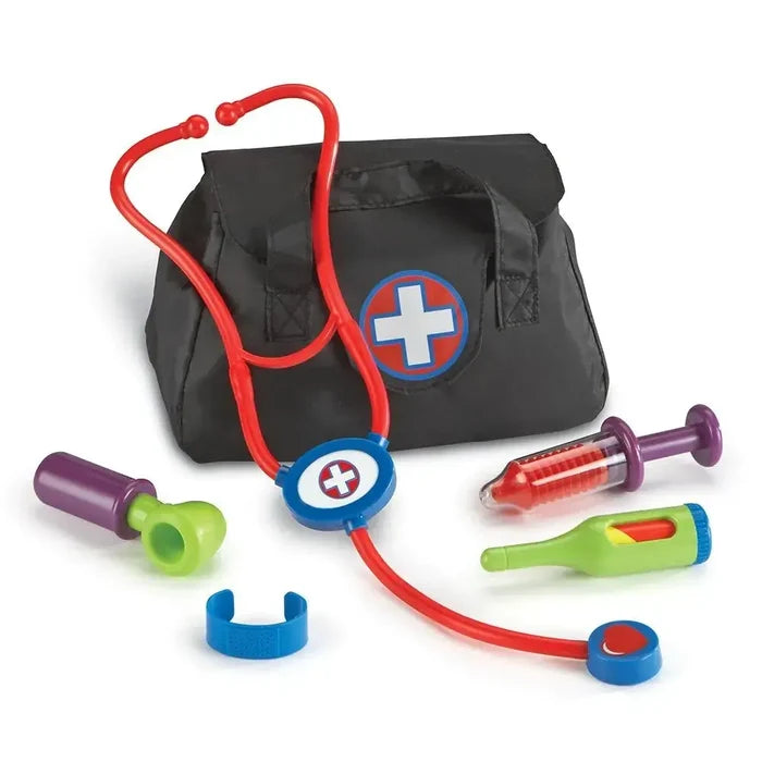 Toy doctor set with red stethoscope, syringe, and thermometer next to a black medical bag with a white cross logo.