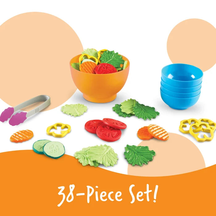 Toy salad set with orange bowl, 4 blue bowls, tongs, and various plastic vegetable pieces on a white background.
