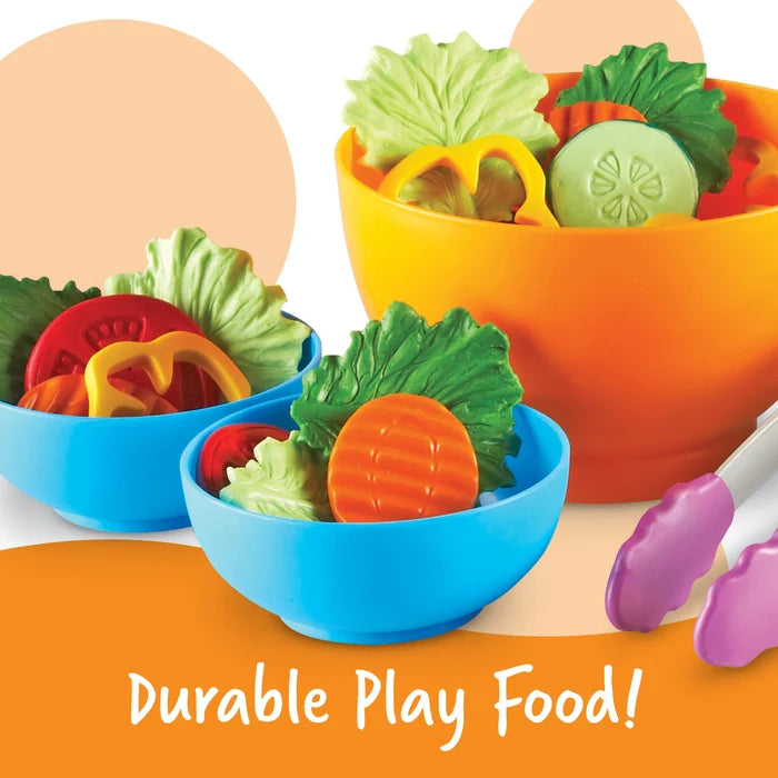 Toy salad set with plastic vegetables in an orange bowl and two blue bowls with purple tongs. Text: Durable Play Food!