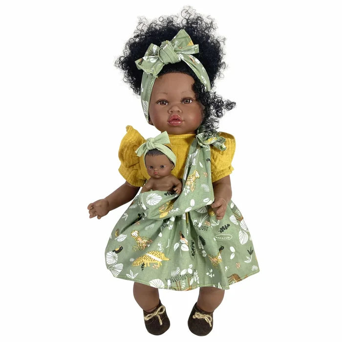 Dark-skinned doll with curly hair, green headband, yellow top, and patterned green dress with a mini doll in a pouch.