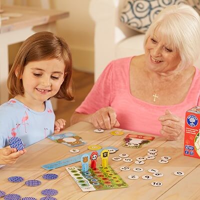 Child and senior playing a counting board game with bear pieces, number tracks, and colorful tokens on a wooden table.