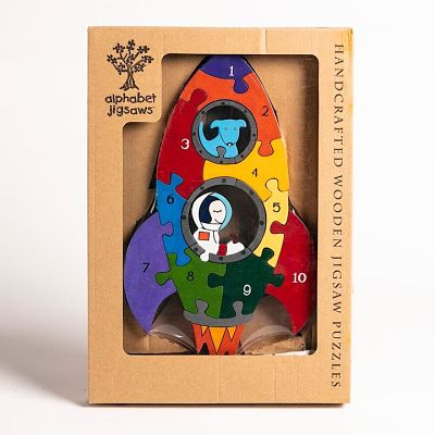 Colorful rocket-shaped wooden puzzle in a box with numbered pieces 1-10, showing a blue dog and astronaut in windows.