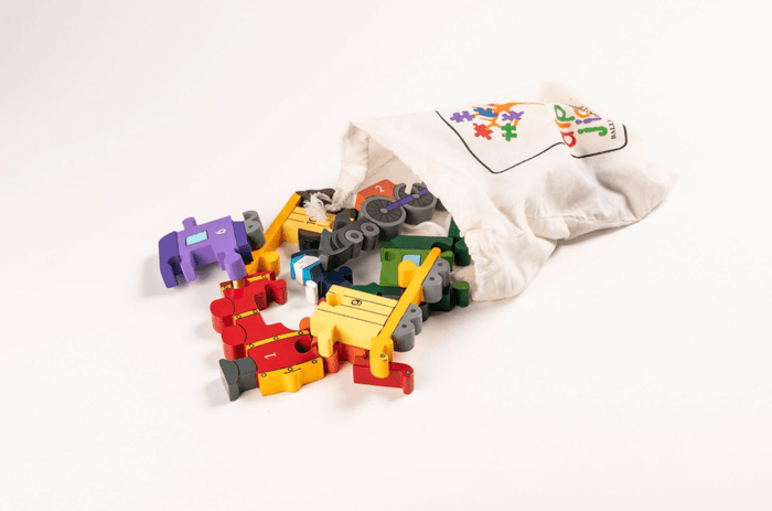 Colorful wooden train puzzle pieces with numbers spilling out of a white drawstring bag on a white background.