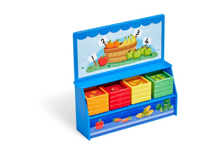 Blue toy market stand with colorful stacked fruit blocks in bins below a numbered fruit illustration backdrop.