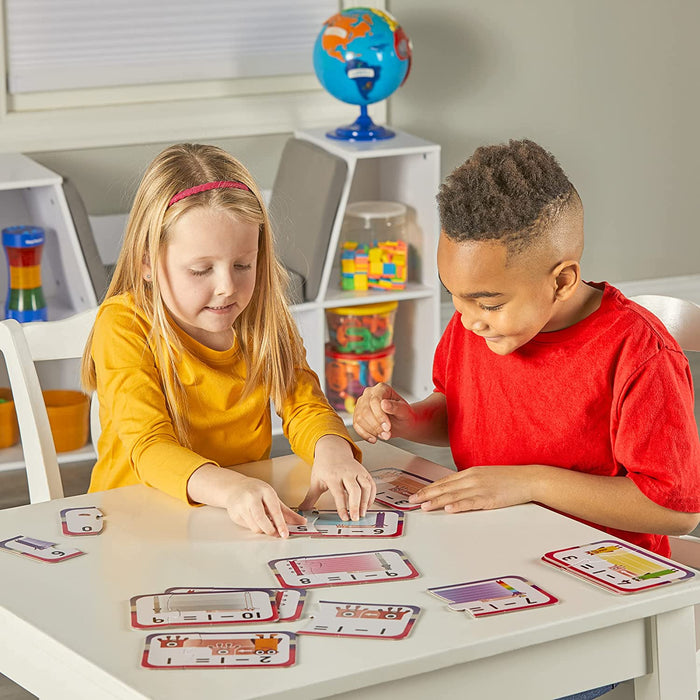 Two kids assembling colorful Numberblocks subtraction math puzzle pieces on a white table.