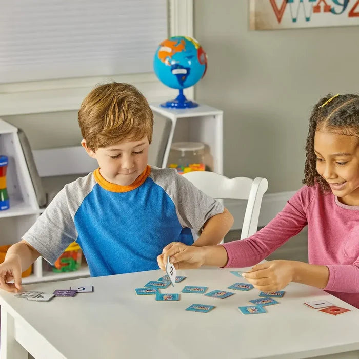 Two children at a white table matching colorful square tiles with Numberblocks characters and numbers.