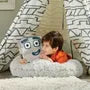 Child lying in a white fluffy seat holding a square grey Numberblock Nine plush toy inside a patterned play teepee.