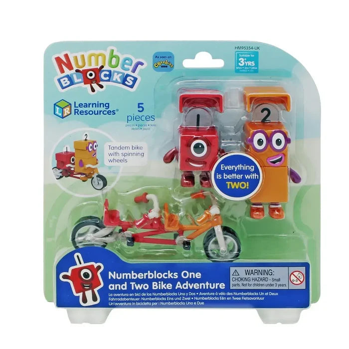Red one-eyed and orange two-eyed block characters with a tandem bicycle in clear plastic retail packaging.