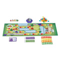 Colorful board game featuring block character figures, a dice popper, cards, square tiles, and bridge scoring trackers.